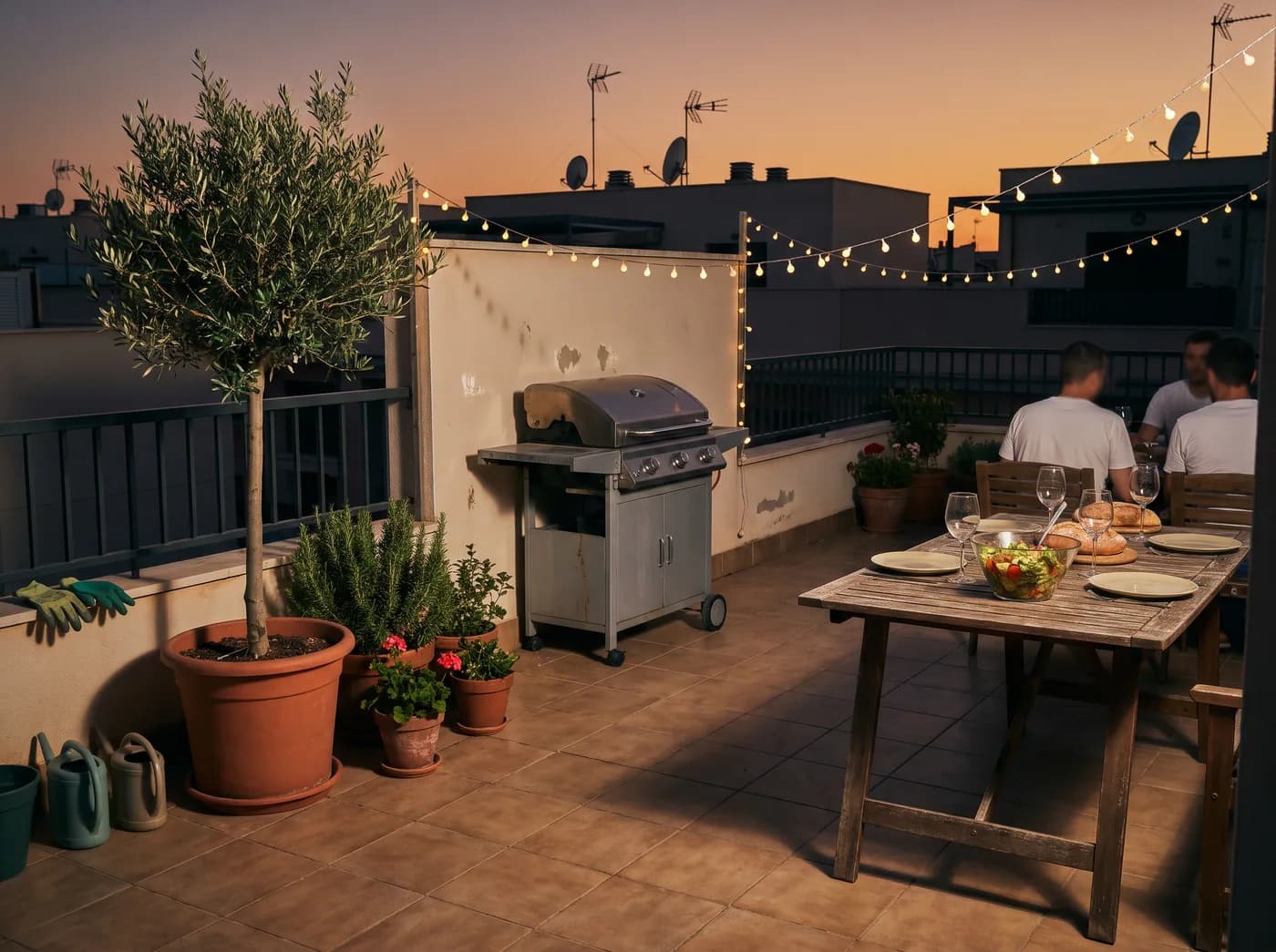 Terraza de un ático al atardecer con una barbacoa de gas de dos quemadores cerrada y una mesa para cuatro (imagen generada con IA)